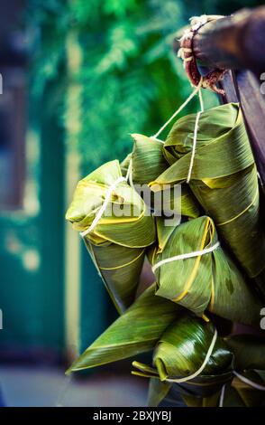 Zongzi multipli che si aggancia sul legno. Zongzi è il famoso gnocchi di riso cinese tradizionale per il Dragon Boat Festival (Duanwu Festival). Foto Stock