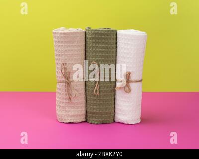 Tre asciugamani in stile ecologico su sfondo rosa e verde. Foto Stock