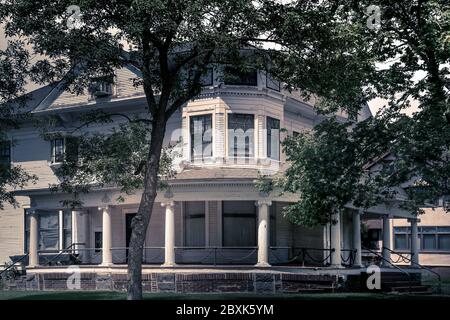 Una vecchia casa a tre piani in stile architettonico Queen Anne con veranda avvolgente e dettagli ringhiera a catena a St. Cloud, Minnesota, USA Foto Stock