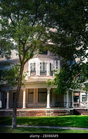 Una vecchia casa a tre piani in stile architettonico Queen Anne con veranda avvolgente e dettagli ringhiera a catena a St. Cloud, Minnesota, USA Foto Stock