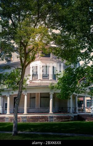 Una vecchia casa a tre piani in stile architettonico Queen Anne con veranda avvolgente e dettagli ringhiera a catena a St. Cloud, Minnesota, USA Foto Stock