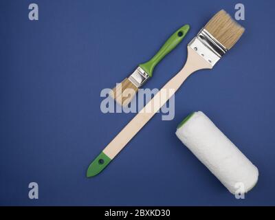 Le spazzole e il rullo. Attrezzo per la finitura della vernice su sfondo blu. Foto Stock