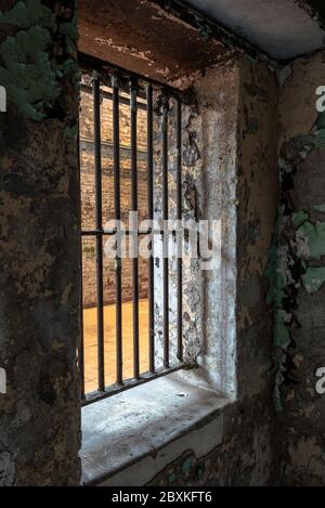 All'interno di una vecchia cella di prigione che guarda fuori attraverso la finestra barrata Foto Stock