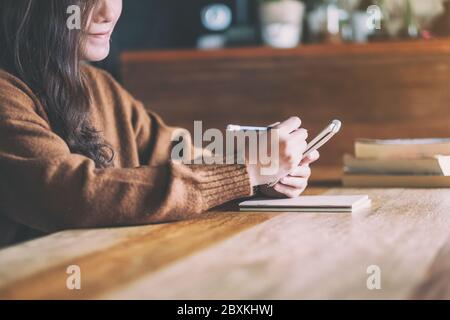 Immagine closeup di una donna che tiene e scrive su un notebook vuoto Foto Stock