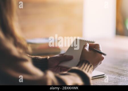 Immagine closeup di una donna che tiene e scrive su un notebook vuoto Foto Stock