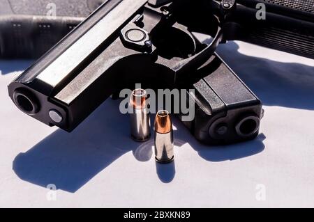 Due pistole semiautomatiche nere, una calibro 40 e una da 9 mm con un proiettile a punta cava per ciascuna accanto a loro su sfondo bianco Foto Stock