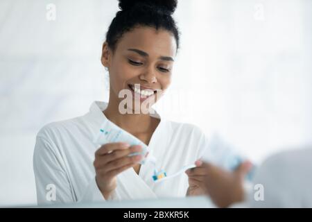 Primo piano sorridente donna afroamericana che applica il dentifricio sullo spazzolino Foto Stock