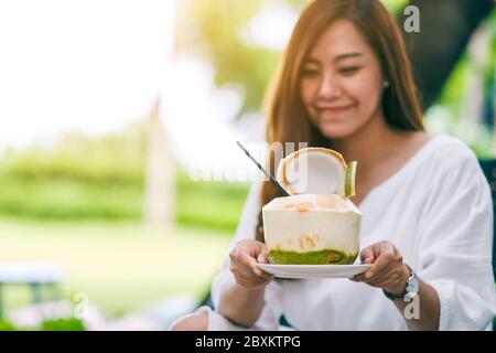 Immagine ritratto di una bella donna asiatica che tiene e beve succo di cocco all'aperto Foto Stock