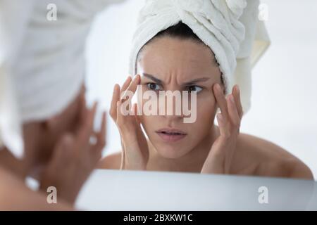 Primo piano donna infelice che controlla la pelle, guardando nello specchio Foto Stock