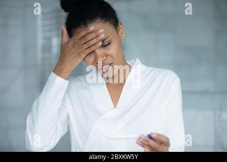 Primo piano infelice stressato donna afroamericana che tiene il test di gravidanza Foto Stock