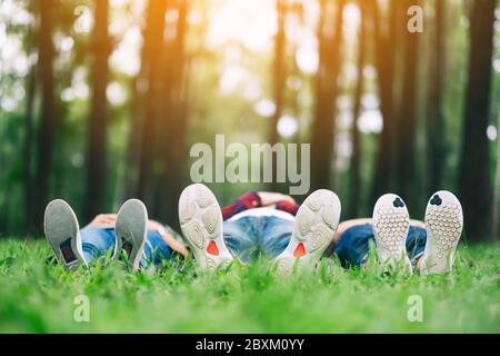 Piedi di un gruppo di giovani mentre si sdraiano su un'erba verde nella foresta Foto Stock