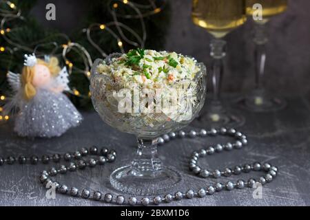 Insalata tradizionale festiva Olivier in vaso di cristallo, servita con vino bianco sullo sfondo delle decorazioni natalizie. Foto Stock