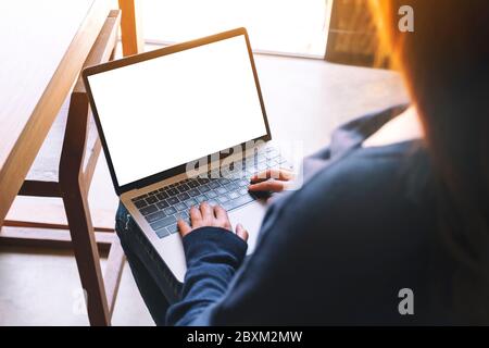 Immagine mockup di una donna che usa e digita sulla tastiera del computer portatile con schermo bianco bianco del desktop Foto Stock