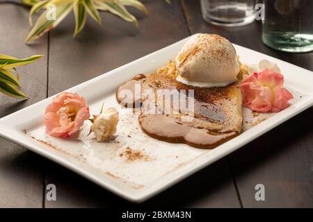 crepe con ripieno di caramello dulce de leche e gelato alla vaniglia su tavolo di legno Foto Stock