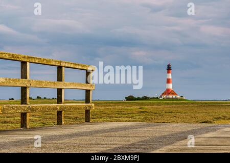 Faro di Westerheversand nelle paludi saline con un piccolo ponte Foto Stock