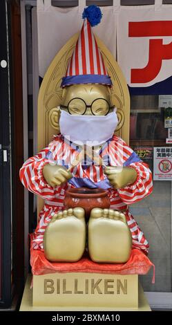 La statua di Billiken che indossa maschere facciali è vista al quartiere dello shopping e del divertimento di Shinsekai a Osaka, Japn il 6 giugno 2020. Foto Stock