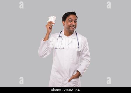 Il medico ha eccitato le pillole di tenuta. Compresse di tenuta del medico. Indiano uomo Dottore con grande idea isolato. Foto Stock