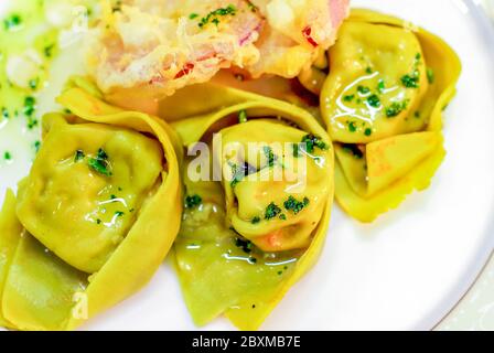 piatto di pasta all'uovo, ravioli di uova e spinaci, farciti con ripieno di ricotta e salsiccia, conditi con burro e salvia, e verdure fritte, per la festa l Foto Stock