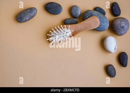 Pietre di Spa con pettine di legno o spazzola di capelli su sfondo giallo, spazio di copia Foto Stock