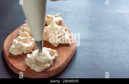 Il processo di creazione di Pavlova dessert, decorazione della meringa con crema Foto Stock
