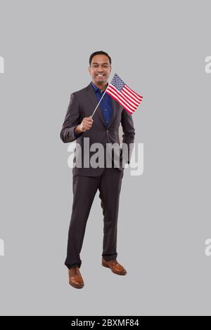 Uomo d'affari che sventolava la bandiera americana. Uomo d'affari indiano in piedi a lunghezza intera con la bandiera degli Stati Uniti in mani Foto Stock