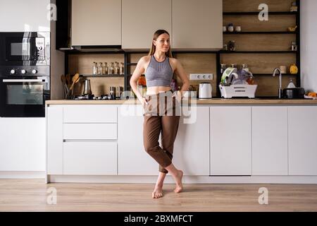 Atmosfera mattutina in una cucina moderna. Bella donna si alza in posa e rilassante. Cucina moderna donna Foto Stock