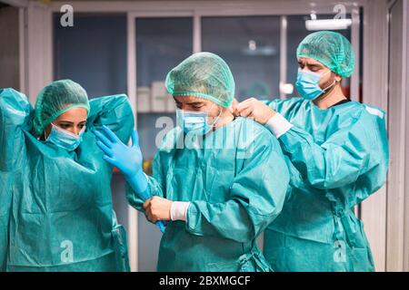 Medici e infermieri si preparano a lavorare in ospedale per l'intervento chirurgico durante l'epidemia di coronavirus pandemic - operatori medici che si vestono all'interno c Foto Stock