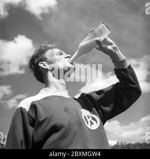 Uomo degli anni '40. L'atleta Åke Spångert sta rinfrescando dopo la pratica e le bevande da una bottiglia del latte sotto il sole. In questo momento il latte è stato venduto e consegnato in bottiglie di vetro o si potrebbe acquistare il latte da portare a casa dal negozio nel vostro biberon. Svezia luglio 1940. 1952 rif 145-4 Foto Stock