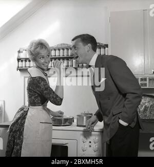 In cucina anni '50. Una giovane coppia in cucina. Gli fa assaggiare il cibo e gli mette un cucchiaio in bocca. Svezia 1959 Kristoffersson rif CG35 Foto Stock