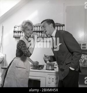 In cucina anni '50. Una giovane coppia in cucina. Gli fa assaggiare il cibo e gli mette un cucchiaio in bocca. Svezia 1959 Kristoffersson rif CG35 Foto Stock