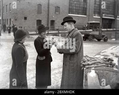 Negli anni '40. I tempi sono duri e l'uomo disoccupato sta cercando di vivere con posti di lavoro temporanei. Qui in una strada di Stoccolma quando si vendono tulipani. Due donne hanno smesso di comprarne alcune. Svezia 1940 Kristoffersson rif 37-9 Foto Stock