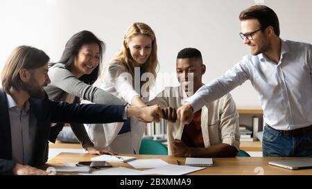 Cinque membri dello staff multirazziale mostrano l'unità impilata mani in cerchio Foto Stock