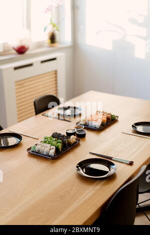 Primo piano di un mix di sushi roll su un tavolo a casa. Aspettando gli amici a mangiare sushi rotoli insieme usando bastoncini di bambù. Foto Stock