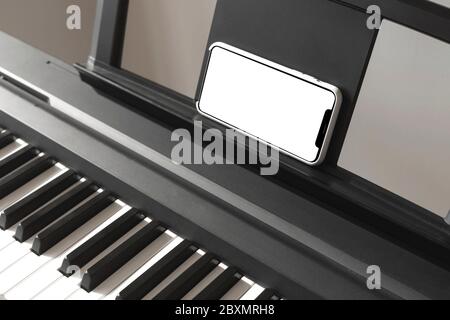 Schermo isolato dello smartphone nelle mani femminili vicino al pianoforte. Foto Stock