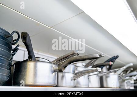 Una vista ravvicinata del fuoco selettivo di pentole e padelle su uno scaffale in una cucina del ristorante Foto Stock