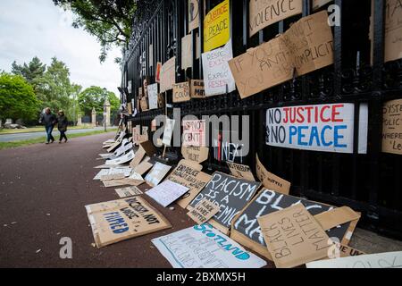 Cartelli e manifesti appesi alle ringhiere del Palazzo di Holyroodhouse dopo il raduno di protesta Black Lives Matter domenica a Holyrood Park, Edimburgo, in memoria di George Floyd ucciso il 25 maggio mentre era in custodia di polizia nella città americana di Minneapolis. Foto Stock