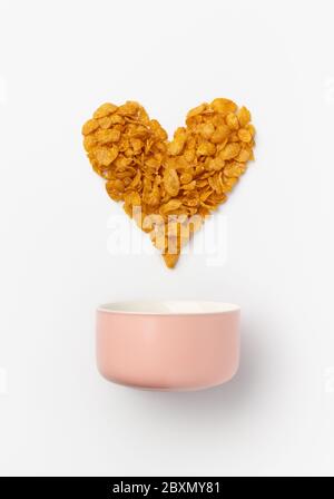 Cornflakes a forma di cuore con ciotola rosa Foto Stock