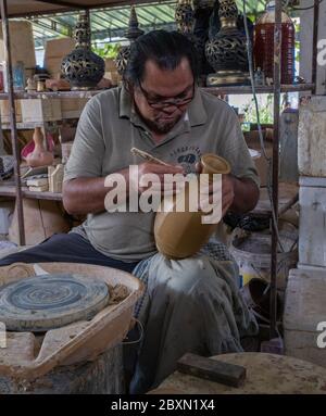 Uomo che intaglia un contenitore di acqua di argilla in un laboratorio di ceramica a Kuala, Kangsar, Perak, Malesia Foto Stock