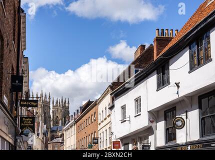 Bassa Petergate in York con i suoi negozi e le torri della cattedrale di York Minster in background Foto Stock