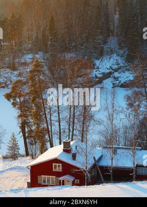 Paesaggio innevato, casa di legno rosso nella neve. Foto Stock