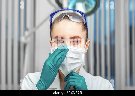 La dottoressa mette su una maschera, lotta contro il virus, dispositivi di protezione individuale, maschere, occhiali, guanti. Il concetto della lotta contro il Foto Stock