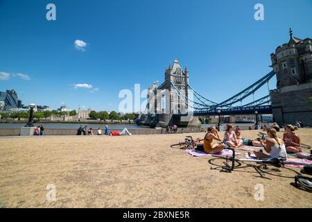 Le persone che si godono la vita all'aperto in una bella giornata di sole sul fiume Tamigi vicino a Tower Bridge, Londra, Regno Unito. Foto Stock