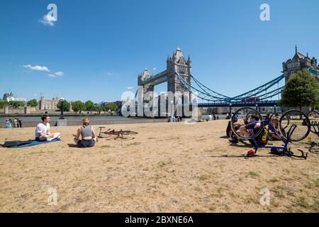 Le persone che si godono la vita all'aperto in una bella giornata di sole sul fiume Tamigi vicino a Tower Bridge, Londra, Regno Unito. Foto Stock