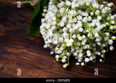 Delicato bouquet di giglio della valle su un tavolo di legno. Bouquet per la vacanza. Messa a fuoco selettiva. Foto Stock
