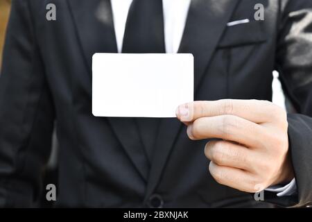 Uomo d'affari che mostra un pezzo di carta vuoto. Qualsiasi idee di disegno di biglietti da visita. Foto Stock