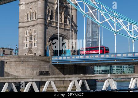 Autobus a due piani rosso di Londra che attraversa Tower Bridge in una bella giornata di sole con cielo blu senza nuvole. Foto Stock