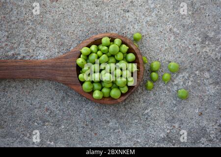 Piselli verdi freschi nel cucchiaio di legno Foto Stock