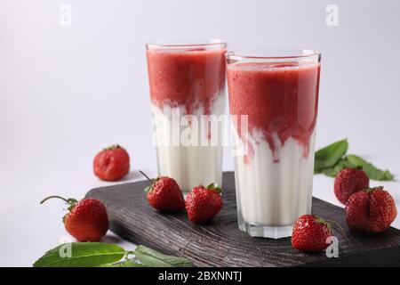 Due porzioni di frullati fatti in casa con fragole fresche, menta e yogurt in bicchieri su sfondo bianco, concetto di Dieta e di controllo della perdita di peso Foto Stock