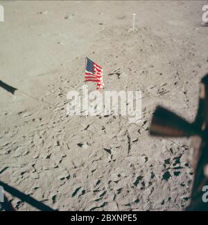 AS11-37-5545 - Apollo 11 - immagine missione Apollo 11 - superficie lunare alla base di tranquillità; ambito e contenuto: Il database originale descrive questo come: Descrizione: Superficie lunare alla base di tranquillità, il sito di atterraggio del modulo lunare (LM). Thruster LM visibili in primo piano. Bandiera degli Stati Uniti visiSe sulla superficie lunare. Immagine tratta dall'interno della LM durante la missione Apollo 11. Il film originale è stato etichettato R. Film Type: EKTACHROME EF SO 168 Color su base in poliestere Estar da 2.5 mil, preso con una lente da 80 mm. Angolo solare basso. Inclinazione approssimativa: Media obliqua. Oggetto: Volo Apollo 11, Luna Foto Stock