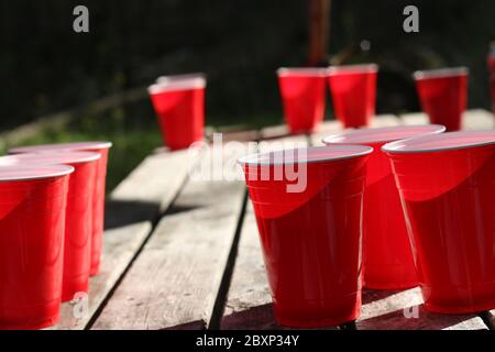 Modello di sfondo a tema Red party CUPS. Sfondo bianco. Contenitore di alcool sul suo lato. La gente balla le mani in aria. Spazio vuoto per la copia Foto Stock